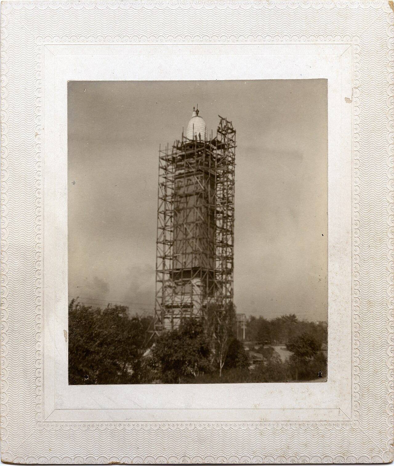 Construction of Compton Heights Water Tower over existing standpipe, with scaffolding around tower and worker at roof level